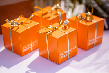 Geschenke für die Absolvent*innen verpackt in orangene Würfel