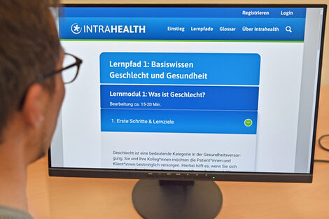 A person looks at a monitor showing the Intrahealth website.