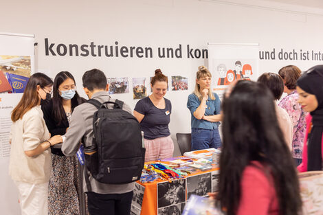 A group of young people stand at an information stand in the entrance area of Fachhochschule Dortmund on Sonnenstraße (House A).