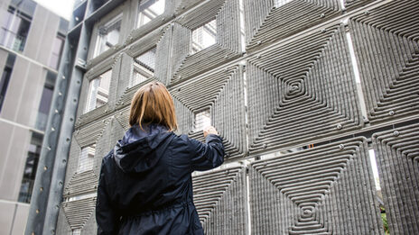 Detailaufnahme: Eine Person steht vor einer robotisch gedruckte Fassade