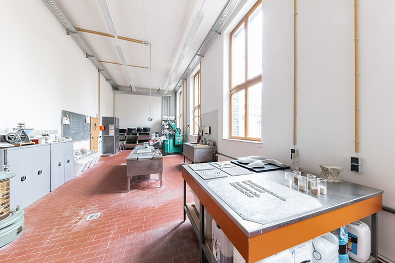 Foto des Betonlabors der Fachhochschule Dortmund, wo unter anderem Betonanfertigungen auf Tischen liegen.