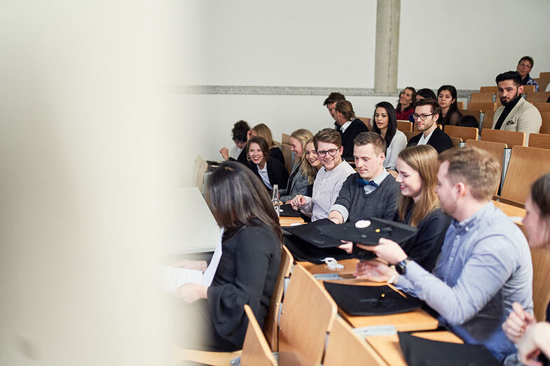 Personen sitzen in einem Hörsaal auf der Werkschau/der Abschlussfeier am Fachbereich Architektur