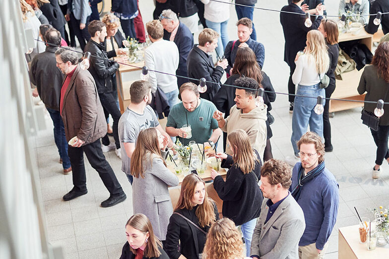 Room where people stand at tables and eat at the work exhibition/graduation ceremony at the Faculty of Architecture