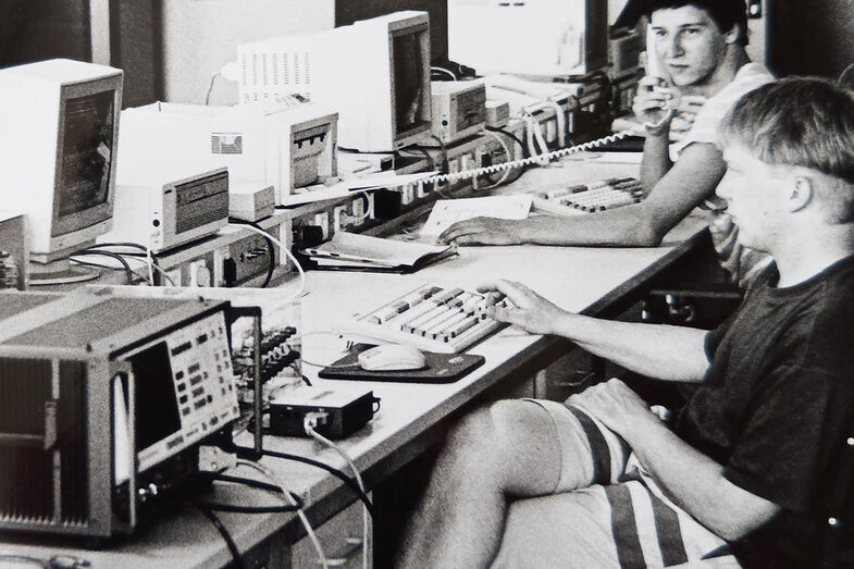 Two students sit in front of electronic devices in the faculty telecommunications picture. The picture is black and white, the technology looks old and quaint by today's standards.