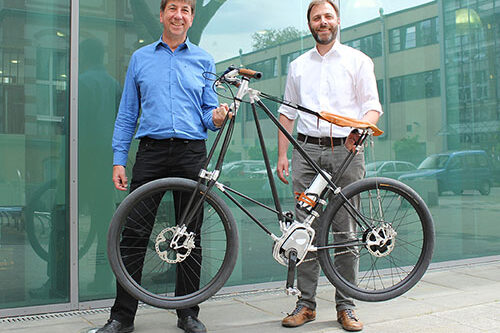 Two men lift a bicycle with one hand.