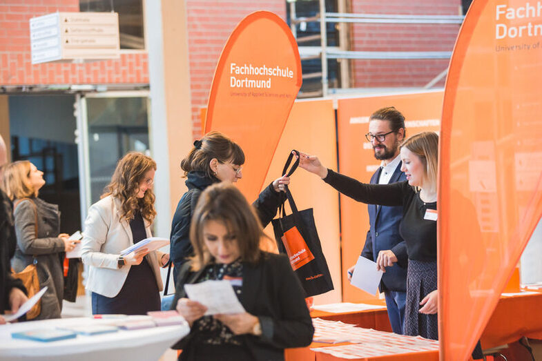 Menschen informieren sich an einem FH Dortmund-Stand.