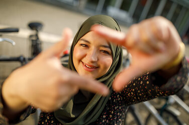 Photo of a student forming a square with her index fingers and thumb in front of her and looking through it.