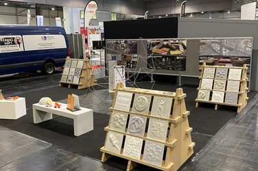 Mehrere Exponate aus Beton stehen in einer Messehalle.