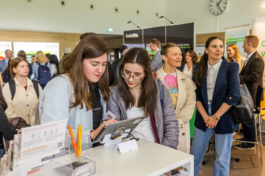 Students explore job offers on a tablet at a company stand.