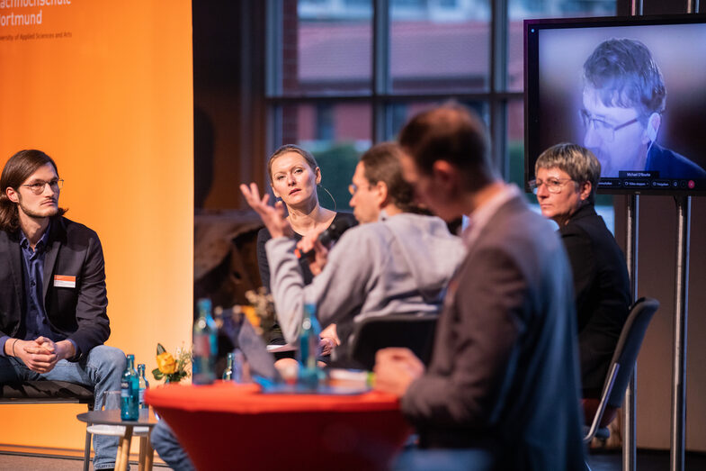 Panel discussion on stage with the moderator  Dr. Dorothea Schostok, the guests  Prof. Dr. Andrea Kienle,  Tobias Kreutzer and  Dr. Nicolas Wöhrl in person and via video call  Prof. Michael O'Rourke.