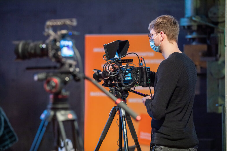 Two cameras directed to the stage operated by one cameraman.