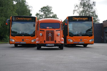 Groß gegen klein: Der Citroën HY in der Mitte von zwei großen, ebenfalls orangefarbenen Stadtbussen der Stadtwerke Dortmund.