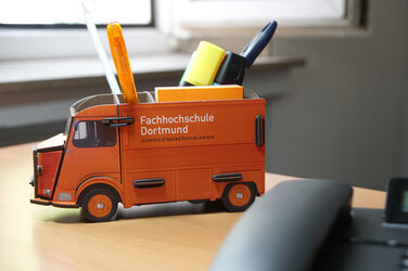 Foto einer Citroen HY-Stiftebox auf dem Schreibtisch mit diversen Stiften darin, im Vordergrund ist ein Telefon im Anschnitt. __ Citroen HY pen box on the desk with various pens inside, a telephone in the foreground is bleed.