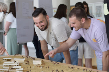 Students look at a model of the surroundings with several single-storey building models made of<br>white cardboard