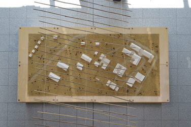 Model supervision with several single-storey building models made of white cardboard,<br>above which is stretched a web of tied bamboo sticks.