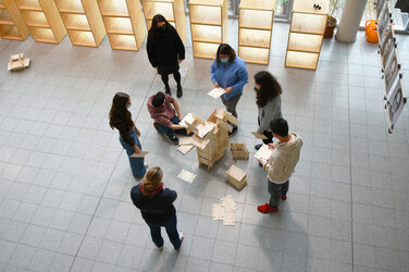 Schüler*innen des Steinbart-Gymnasiums Duisburg beim Zusammenstecken der Kartenskulpturen von der Empore fotografiert.