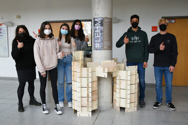 Gruppenbild der Schüler*innen des Steinbart-Gymnasiums Duisburg mit ihrer fertiggestellten Steckkartenskulptur. Alle Personen recken ihren Daumen nach oben.