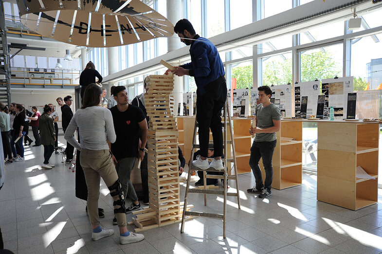 Besucher*innen des Tags der offenen Tür am Fachbereich Architektur bauen einen Turm aus Holzblöcken