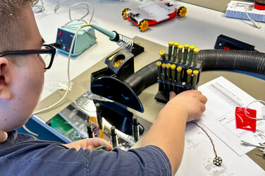 A person is sitting at a table and working with technical equipment.