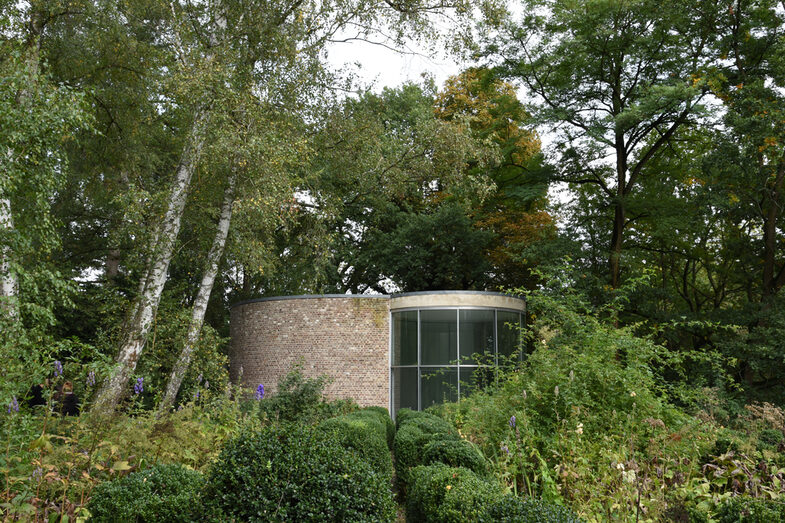 A small building between bushes and trees