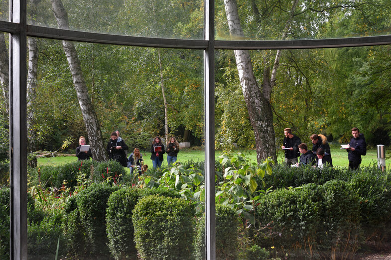 People hold blocks and pens in their hands and look at plants.