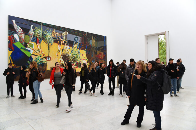 Personen gehen durch eine Galerie. Im Hintergrund befindet sich ein großes Gemälde.