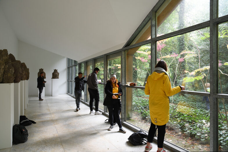 People stand in a gallery and look out of the window.