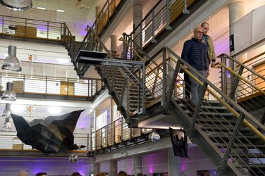 View into the foyer of the faculty, which is filled with guests and illuminated in purple.