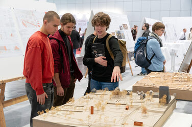 Visitors take a look at the exhibited design plans and the corresponding models by the winners of the trade fair academy.