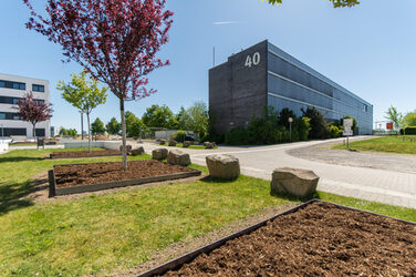 Photo of the building at Emil-Figge-Straße 40 of the Fachhochschule Dortmund. In the foreground a meadow with planted trees and sidewalks.