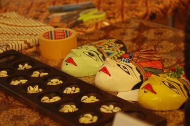 Bunte Masken und ein traditionelles Brettspiel auf dem Tisch des Kulturstands Indonesien