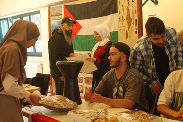 Am Kulturstand Marokko schmücken Studierende den Tisch und bereiten mitgebrachtes Essen darauf vor.
