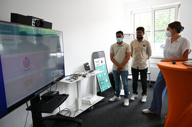 Zwei Studenten präsentieren die Benutzeroberfläche des Flutwarnungssystem auf einem großen Monitor