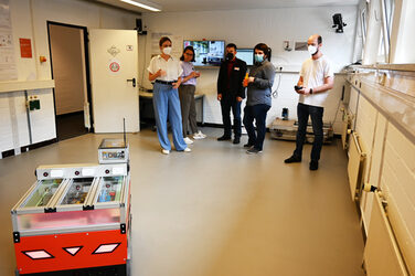 Eine Gruppe schaut sich einen mobilen Roboter im Roboterlabor des IDiALs an.
