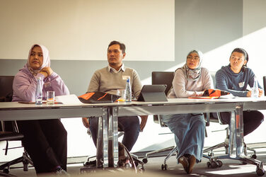 Four people sit at a table and look to the left with interest__Four people sit at a table and look to the left with interest