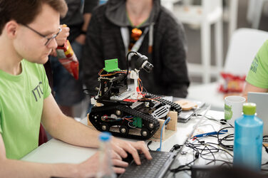 Eine Person sitzt an einem Tisch mit einem Roboter.