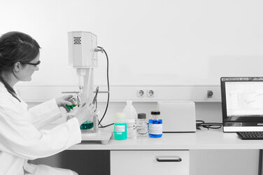 A woman works in a laboratory with various liquids.