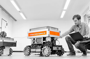 Zwei Studierenden arbeiten ein einem mobilen Robotersystem.
