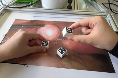 In the photo of an operation, there are cubes with QR codes, two hands reach for the cubes.