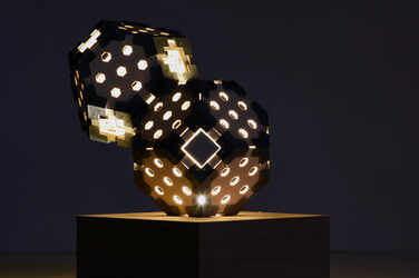 Nachtaufnahme einer erleuchtenden, skulpturalen Hexagon Leuchte auf einem Holzsockel mit generativ gefertigten Elementen
