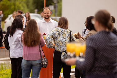 Mehrere Personen unterhalten sich an einem Stehtisch in freudiger Stimmung.