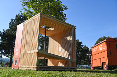 The Fachhochschule Dortmund's wooden seating cube is located in a green area near the Westfalenhallen subway station.