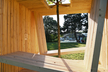 The Fachhochschule Dortmund's wooden seating cube is located in a green area near the Westfalenhallen subway station.