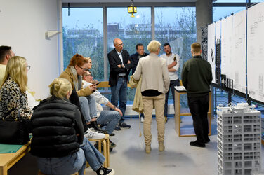 Graduates and guests at the exhibition in front of the plans for a Bachelor's thesis in the faculty galleries.