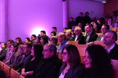 Rows of seats in the lecture hall with graduates and their families and friends.