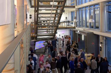 View from a gallery into the foyer of the faculty, which is filled with guests.
