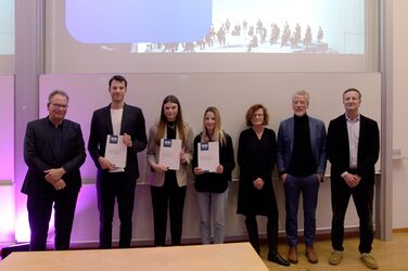 Lecturers and the three winners of the "wettbewerbe aktuell" award on the stage of the lecture hall.