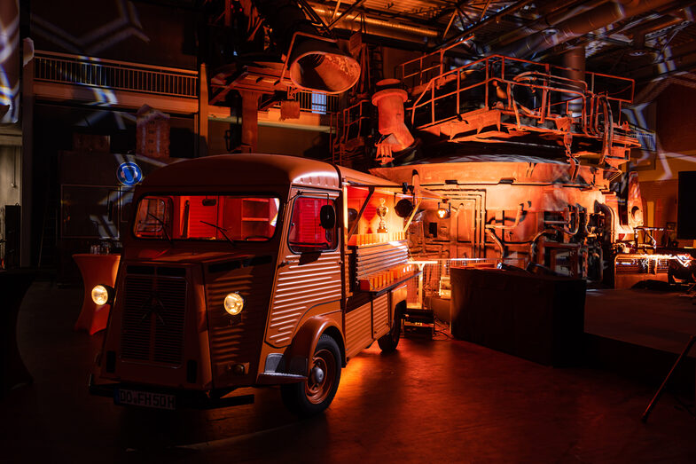 Photo of an illuminated hall. Inside is a Citroen HY with the side flap open.