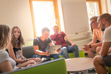 Photo of a group of students sitting on a couch in the lounge area and chatting.