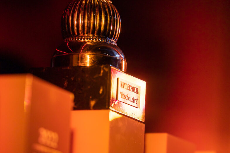 Photo of four orange cubes. There is a trophy on one of the cubes.